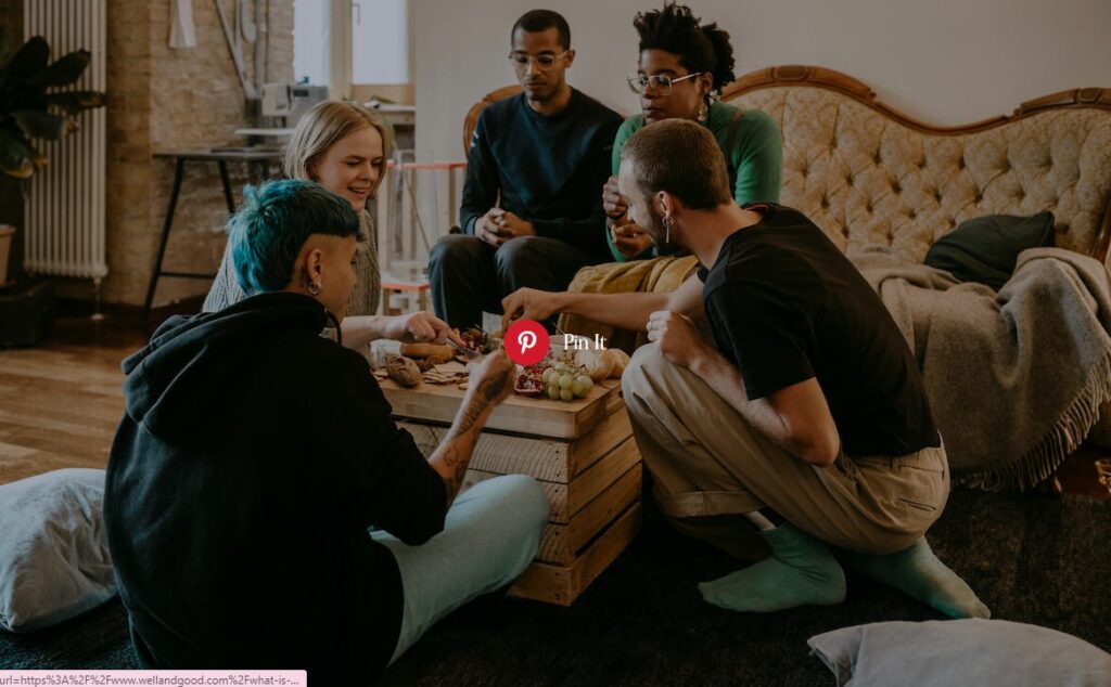five people sit around a coffee table eating cruidite